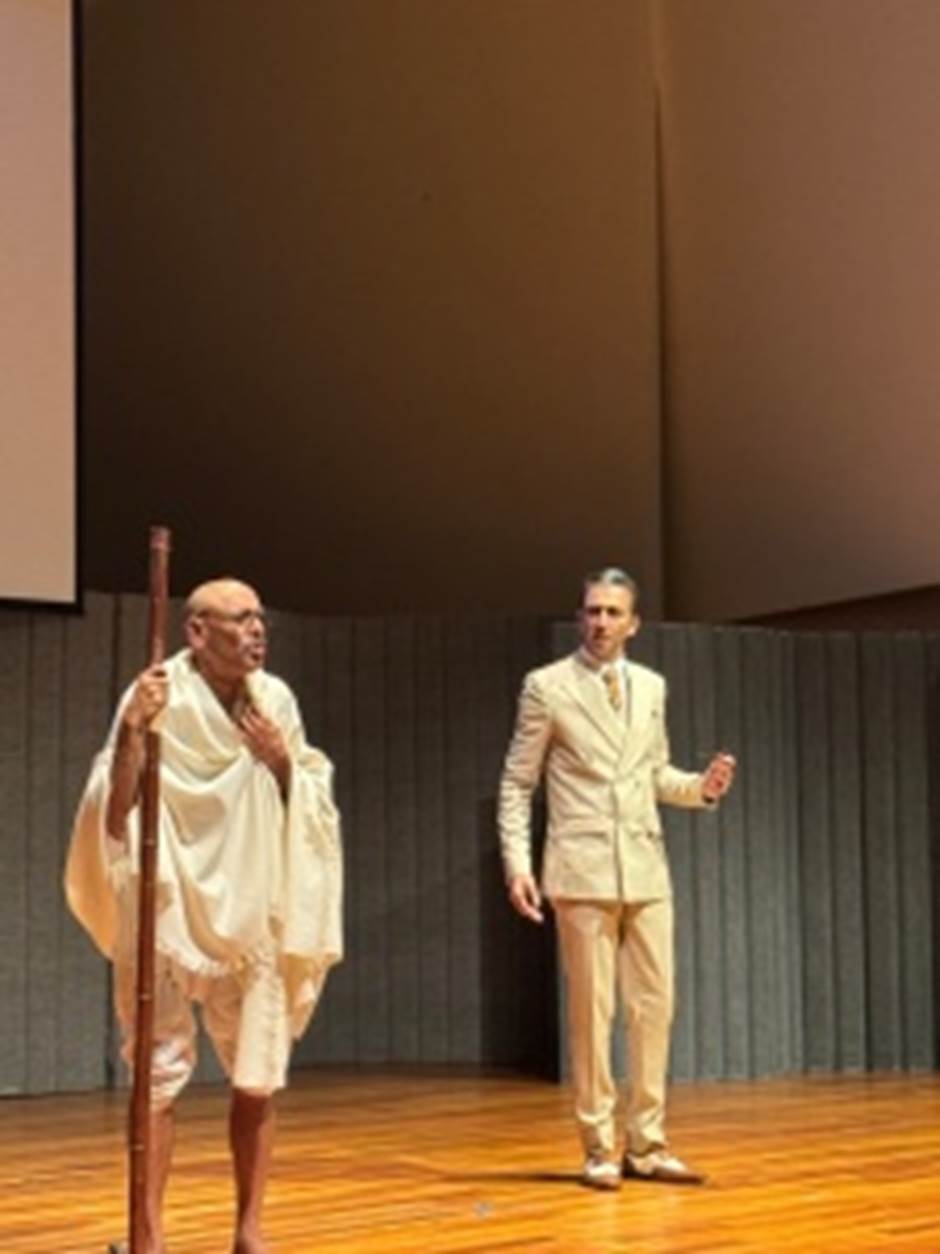 A person in a white robe standing on a stage  Description automatically generated