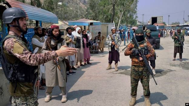 FILE - A Pakistani paramilitary soldier, left, and Taliban fighters stand guard on their respective sides at a border crossing point between Pakistan and Afghanistan, in Torkham, in Khyber district, Pakistan, Sept. 5, 2021. 