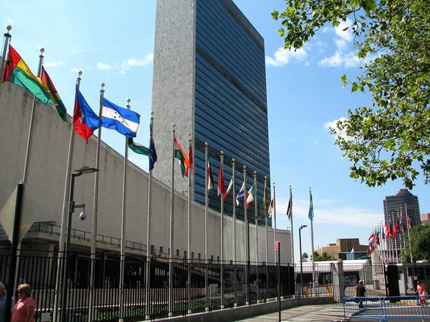 A group of flags in front of Headquarters of the United Nations  Description automatically generated