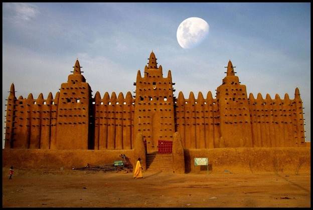 A large building with a moon in the background with Great Mosque of Djenné in the background  Description automatically generated
