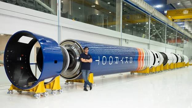 A person standing next to a large blue and white cylindrical object  Description automatically generated