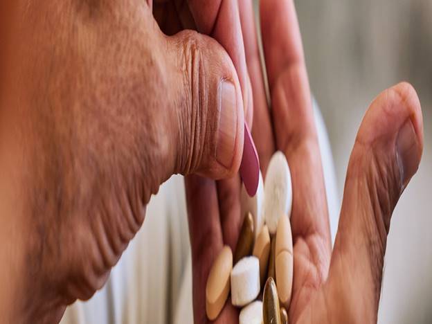 Hand holding various supplement tablets