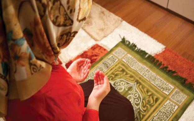 A person in a red shirt and a scarf praying  Description automatically generated