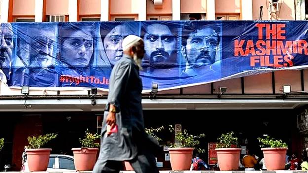 A man walks past a banner of Bollywood movie 'The Kashmir Files' installed outside a cinema hall in the old quarters of Delhi on March 21, 2022