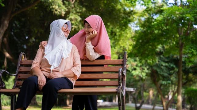 Two women sitting on a bench  Description automatically generated