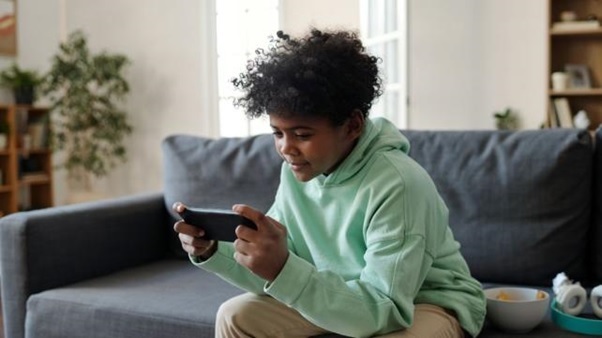 A young person sitting on a couch playing a video game  AI-generated content may be incorrect.