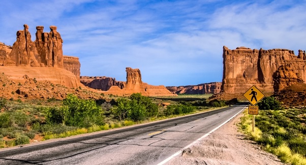 A road with tall rock formations with Bamburgh Castle in the background  AI-generated content may be incorrect.