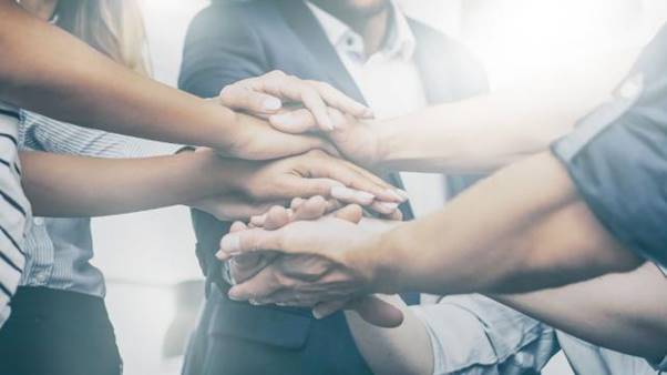 A group of people putting their hands together  AI-generated content may be incorrect.