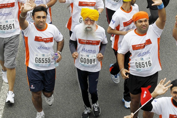 Fauja Singh, wearing a yellow turban and running gear runs with others