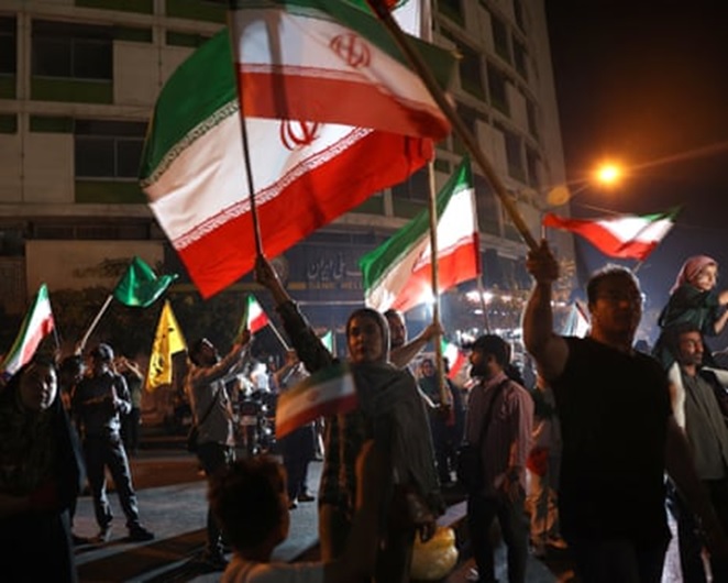 A night-time shot of people waving Iranian flags on a street