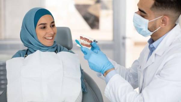 A dentist showing a person how to brush her teeth  AI-generated content may be incorrect.