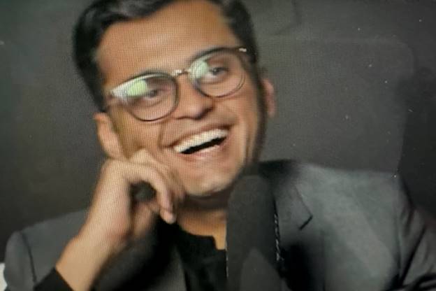 A person in glasses smiling  Description automatically generated