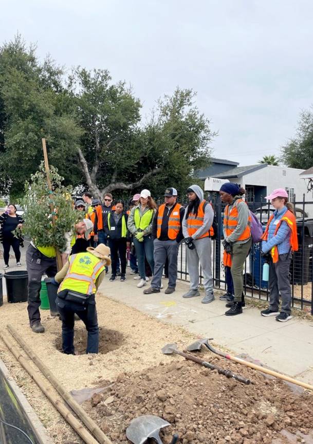 A group of people in vests standing next to a fence  Description automatically generated