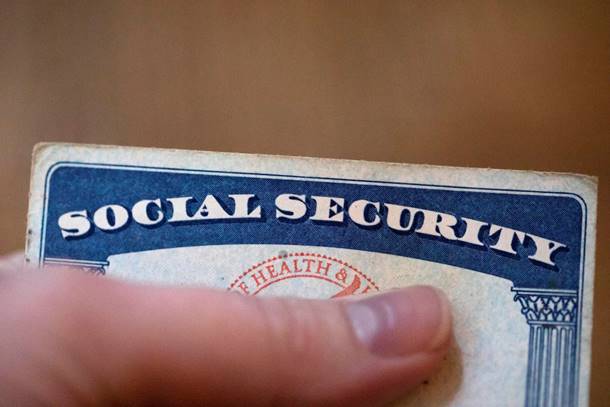 A finger holding a social security card  Description automatically generated