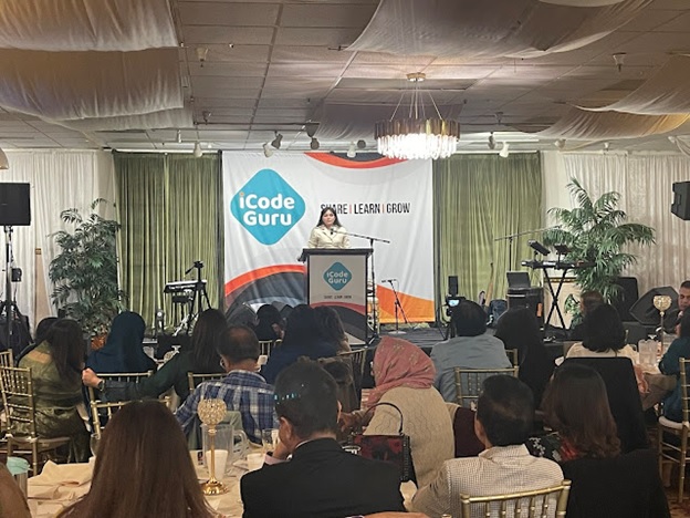 A person standing at a podium in front of a group of people  AI-generated content may be incorrect.