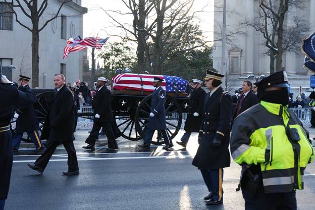 A funeral procession with a coffin  Description automatically generated