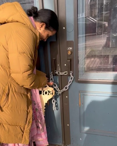 A person in a coat holding a padlock  AI-generated content may be incorrect.