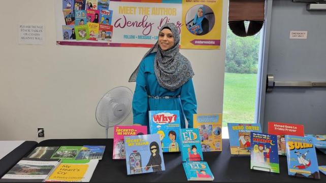 A person standing in front of a table with books  AI-generated content may be incorrect.