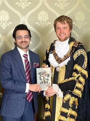 A person in a suit holding a book  AI-generated content may be incorrect.